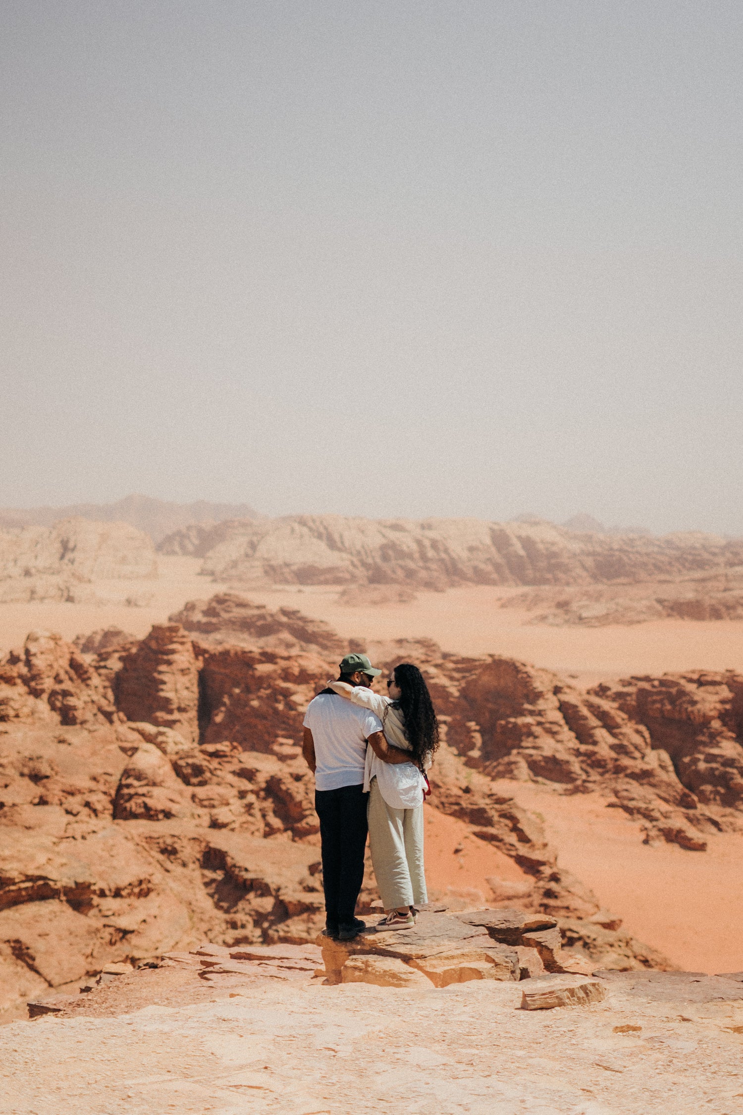 Couple embracing on a rocky outcrop with desert landscape in the background