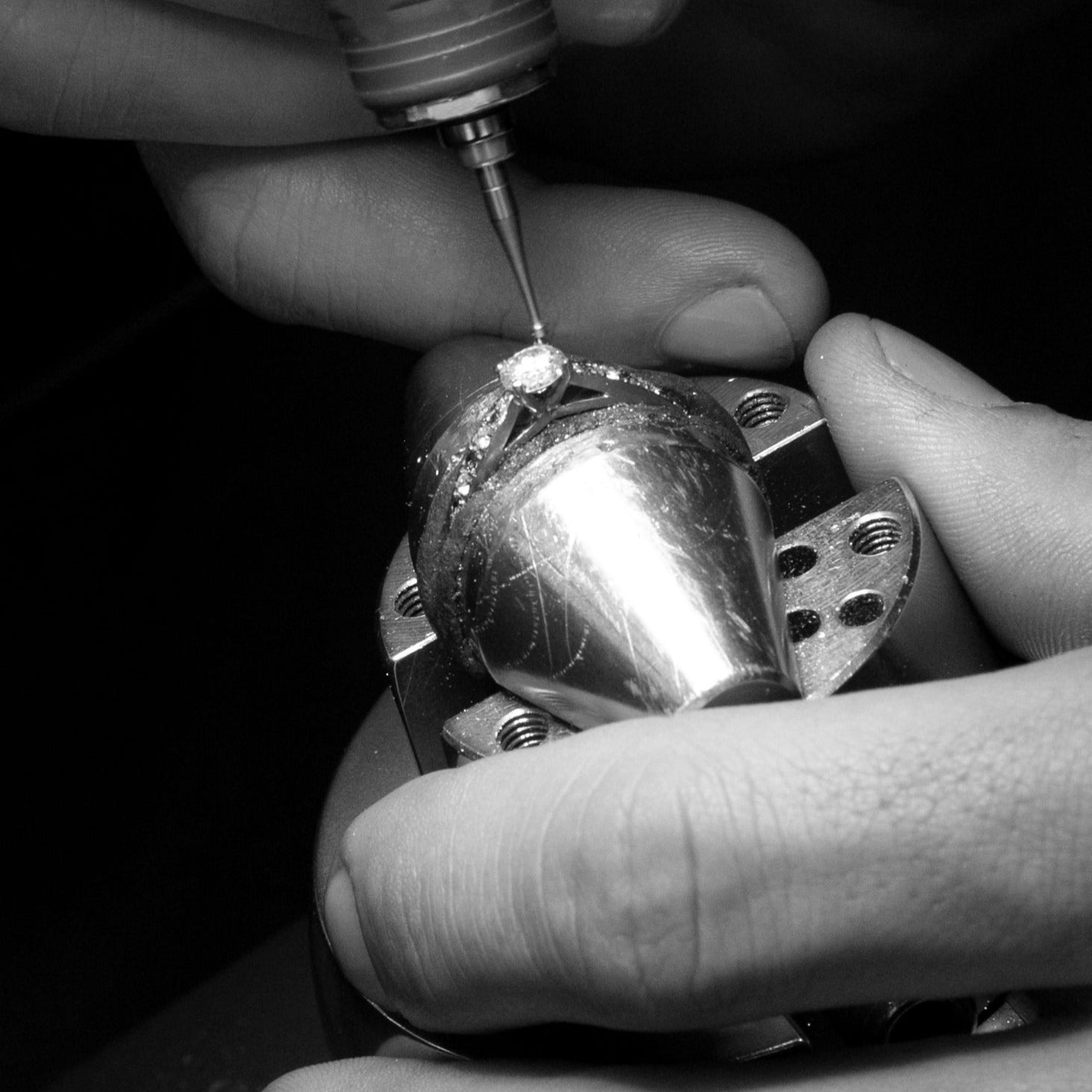 Close-up of a diamond being set into a metal piece with a drill bit.