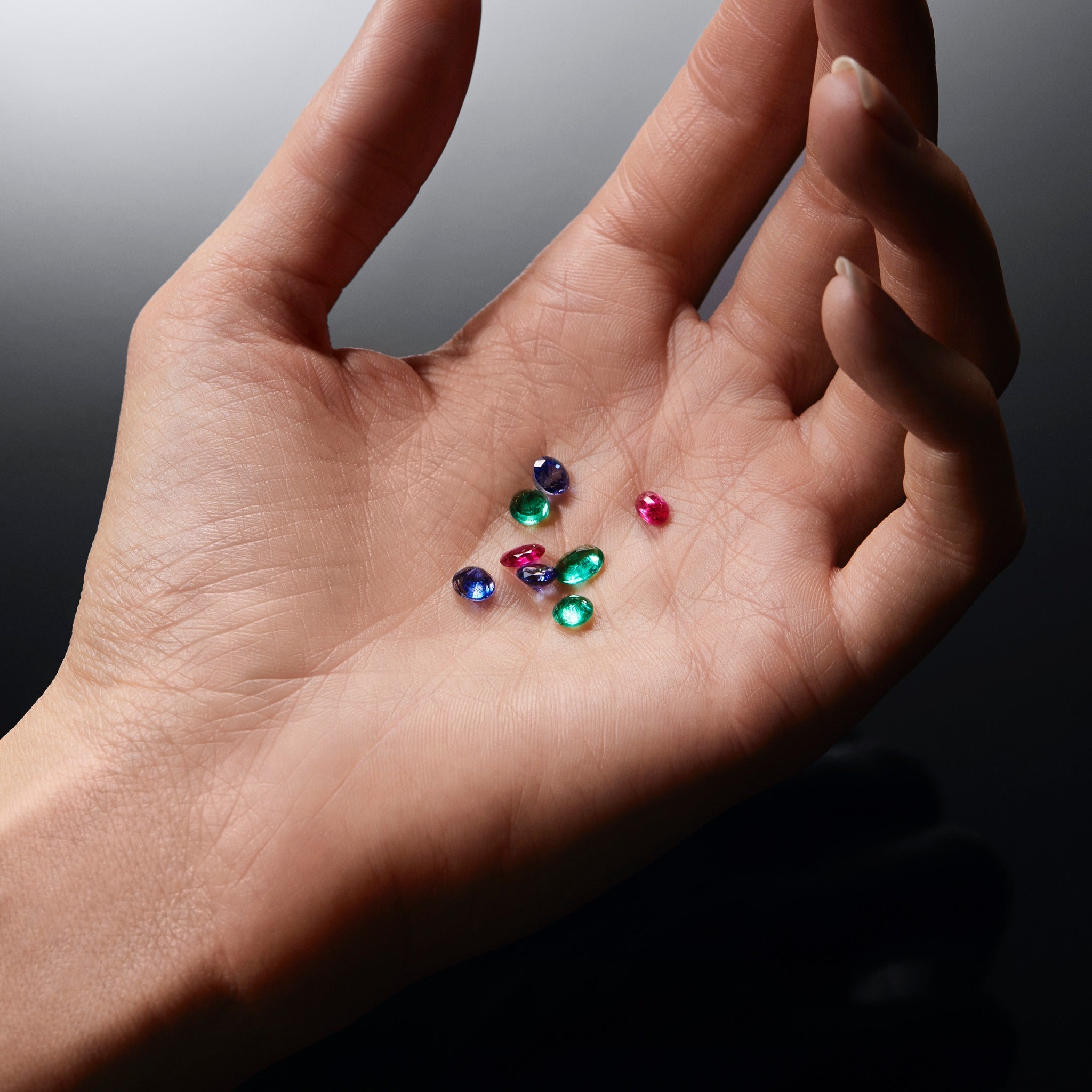 Hand holding multicolored gemstones against a dark background