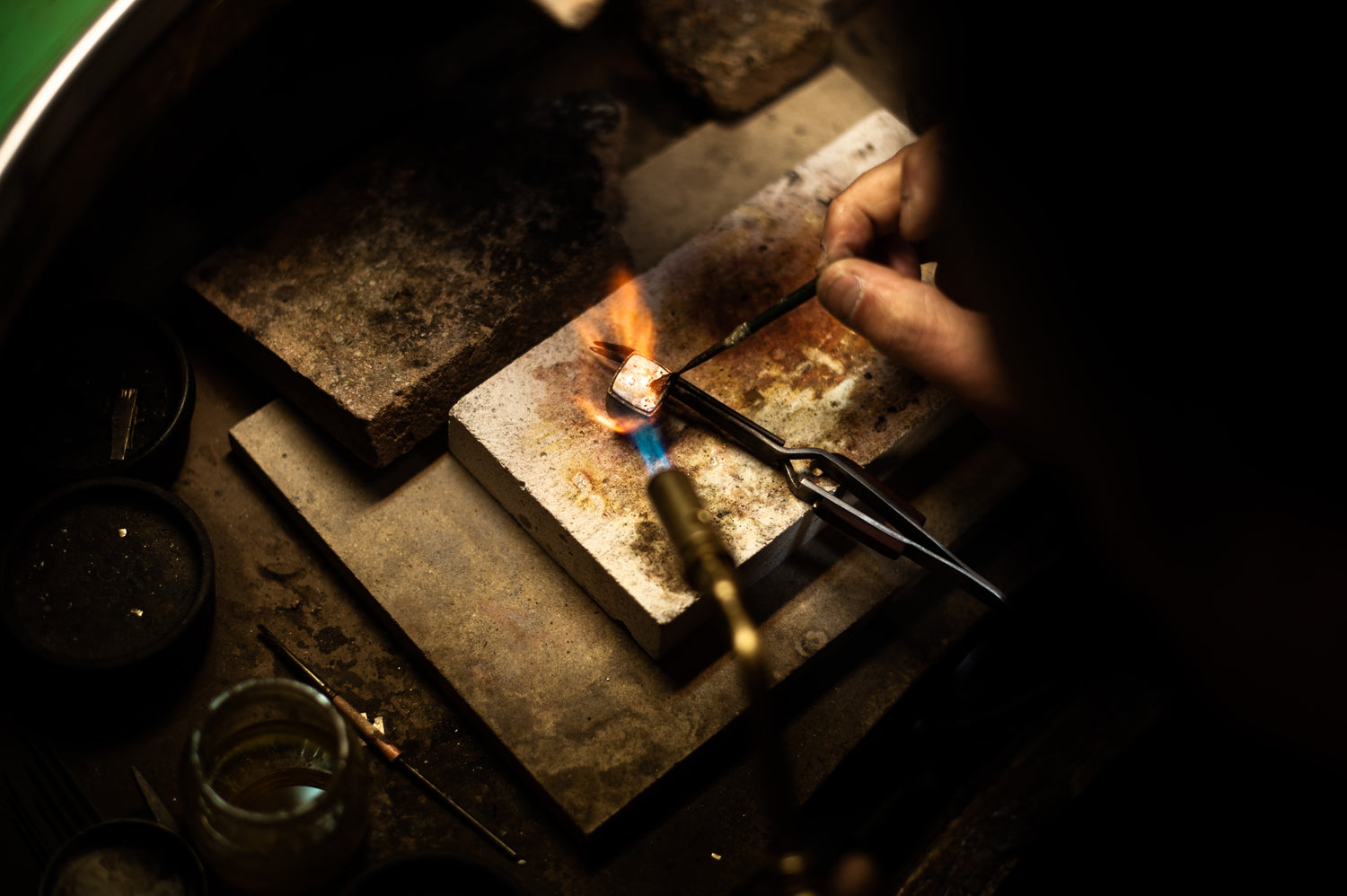 Person using a torch to heat metal on a anvil