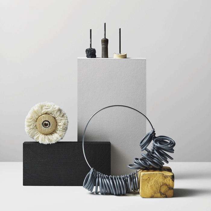 Goldsmith tools and ring sizer on a white surface with a neutral background