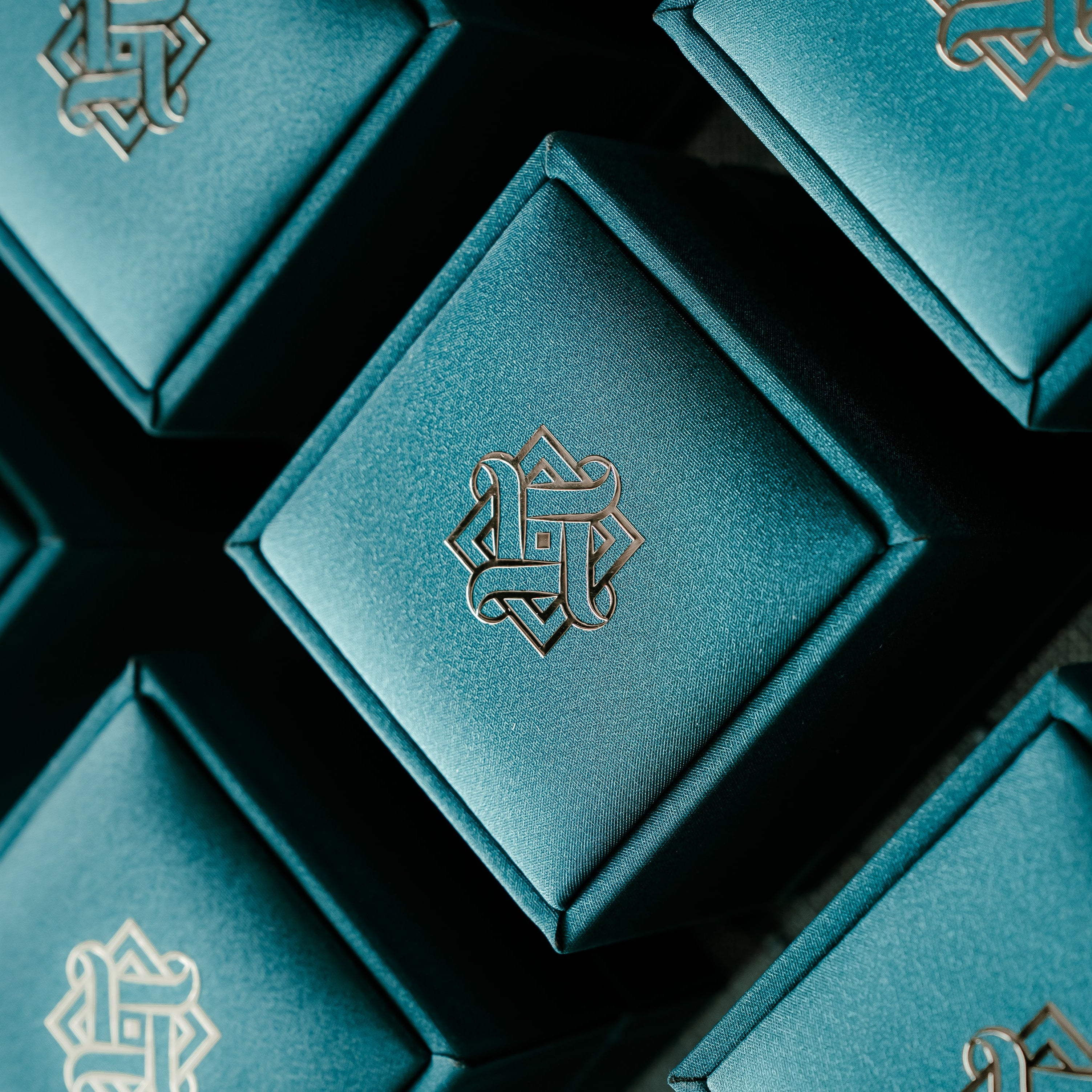 Teal jewelry boxes with Hafeez logo on a dark background