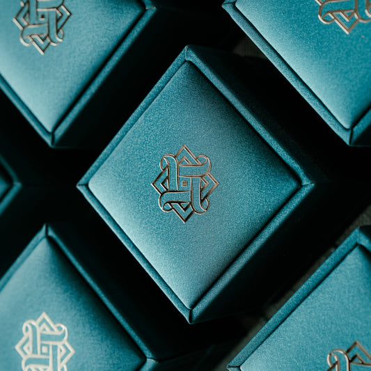 Teal jewelry boxes with Hafeez logo on a dark background
