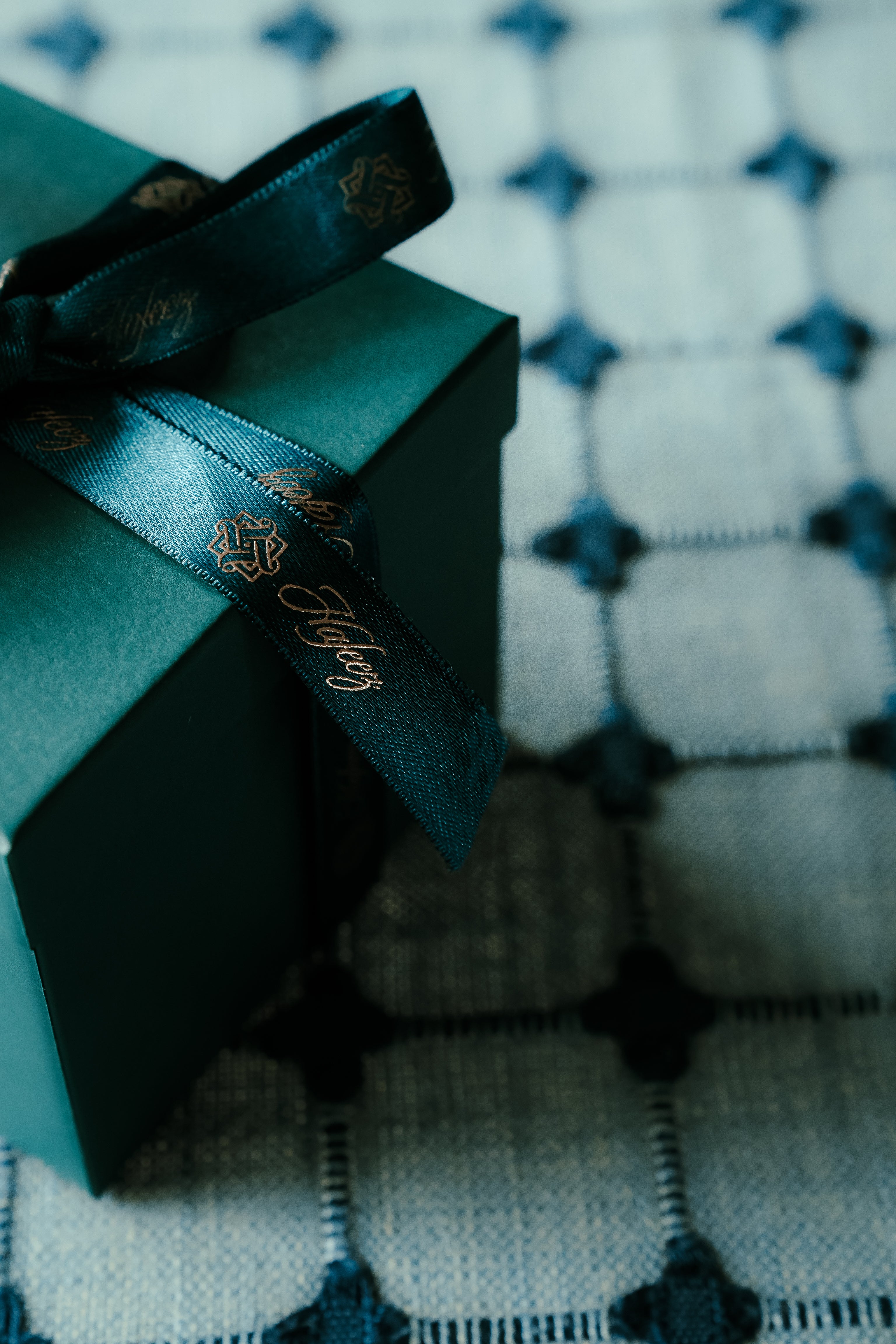 Hafeez teal gift box with a ribbon on a patterned fabric background
