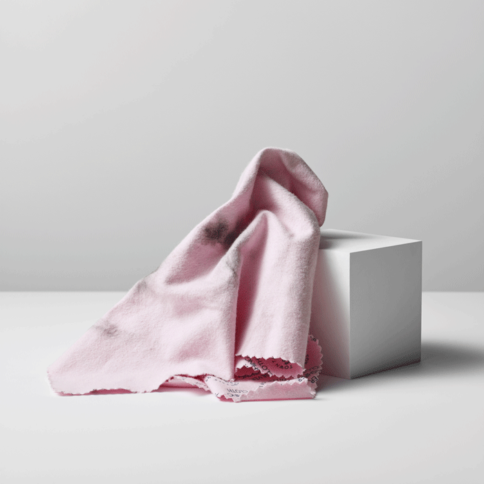 Pink fabric draped over a white cube on a light gray background
