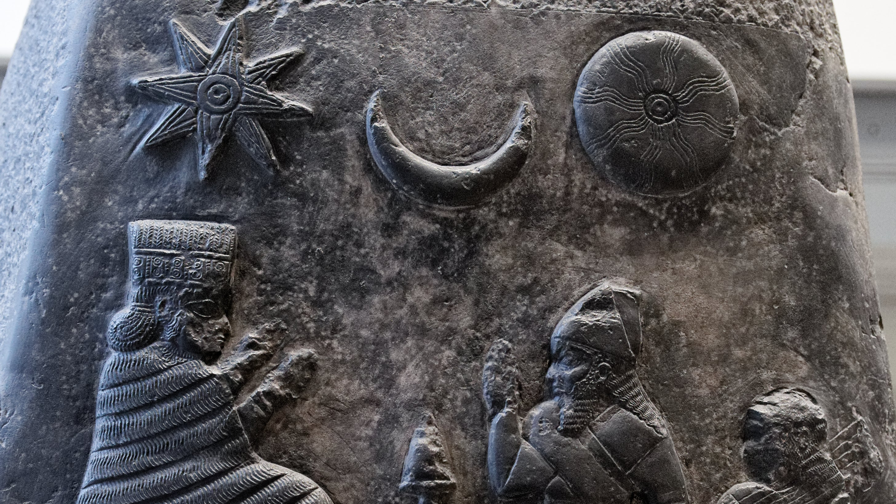 Carved stone panel with star, moon, and human figures