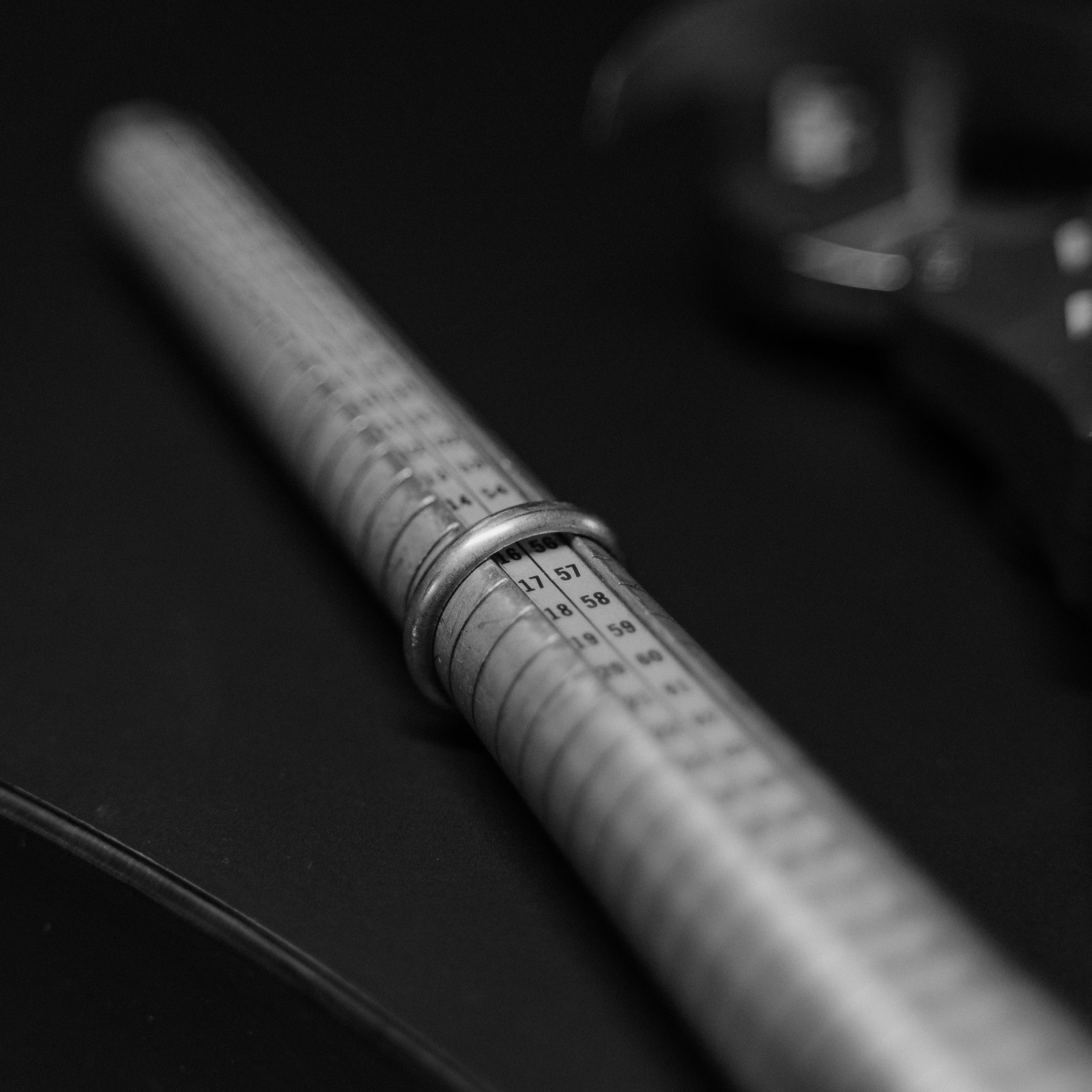 Close-up of a ring sizer with measurement markings and a ring on a dark background