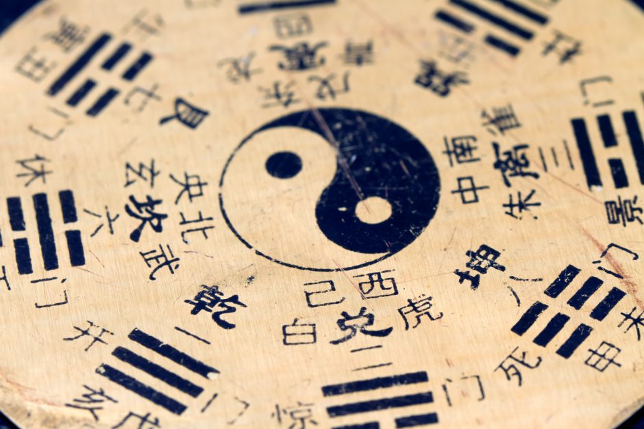 Yin Yang symbol surrounded by Chinese characters on a textured background