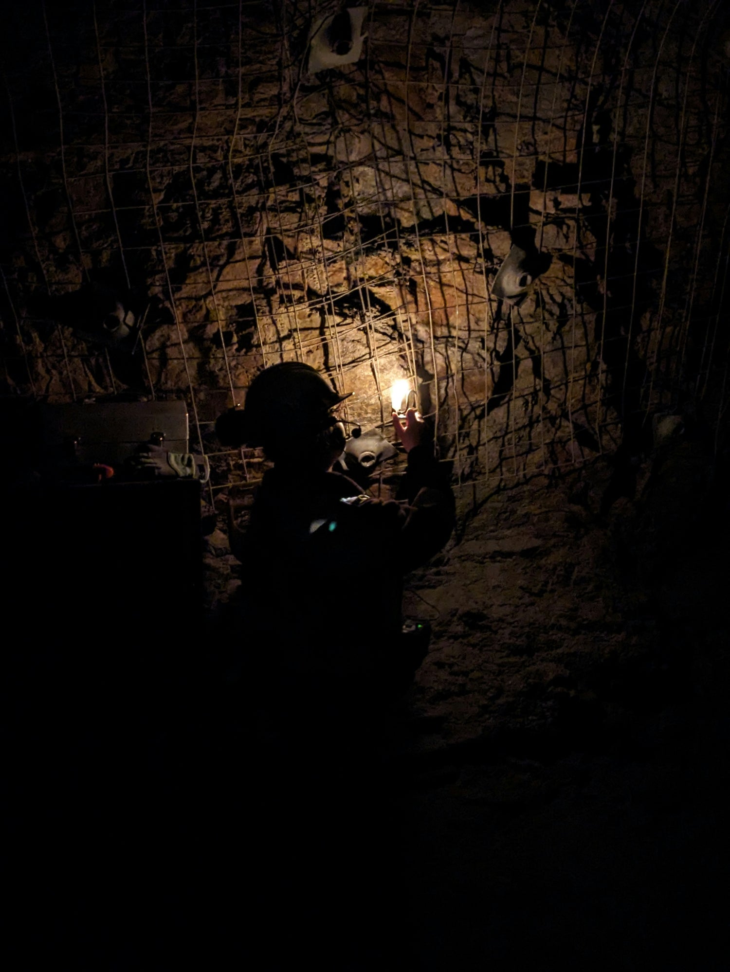 Person holding a light source in a dark, textured tunnel.